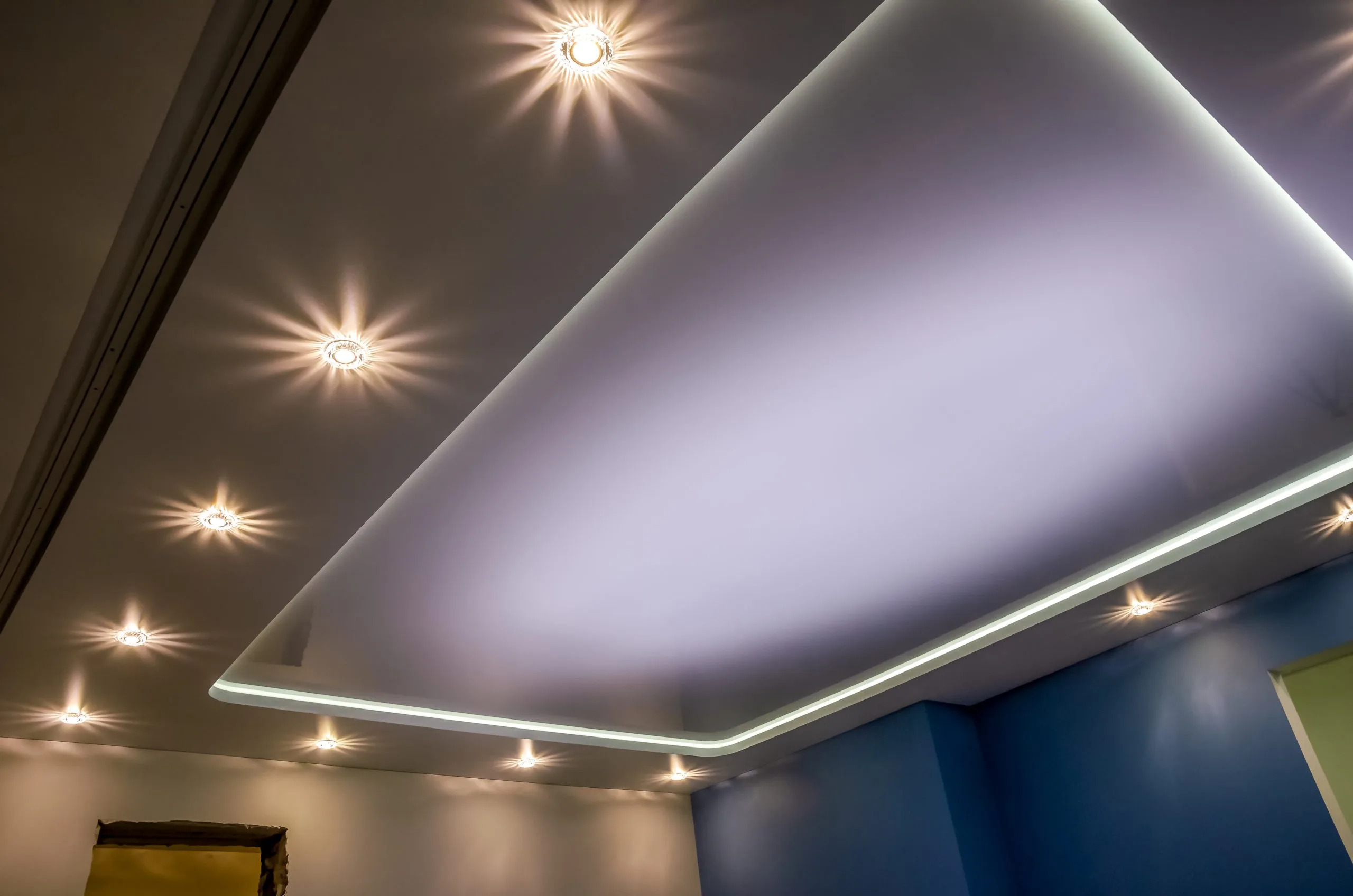 Bright ceiling lights illuminate a room with blue walls and a soft glow
