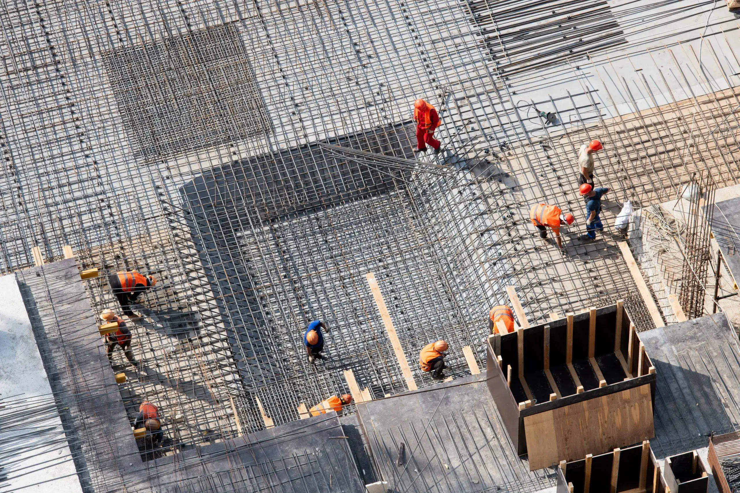 Workers are constructing a building, laying rebar and preparing concrete foundations